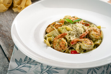 Flavorful shrimp pasta in a luscious sauce, adorned with cheese and basil, served on a white plate with a decorative cloth backdrop. Great for a delightful and hearty dinner, close up