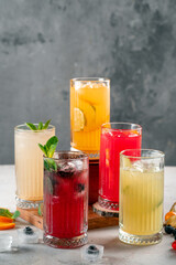 Five different glasses of lemonade on the table, drinks with berries and citrus fruits