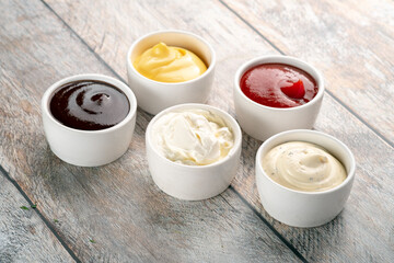 Different sauces on a wooden background - ketchup, barbecue, zaziki, mayonnaise, cheese.