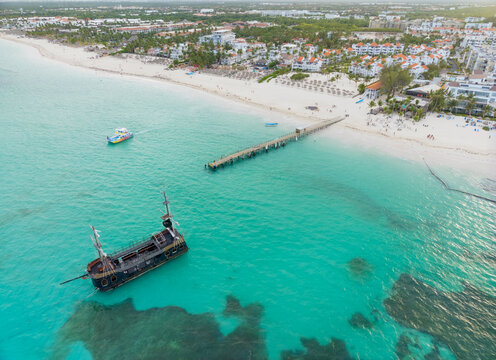 A large ship is docked at a pier on a beach
