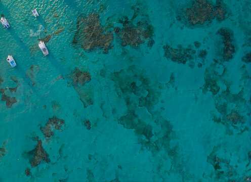 A blue ocean with a few boats floating on it
