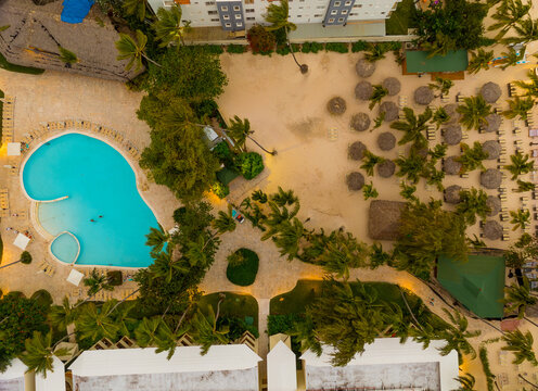 A pool and a beach area with palm trees