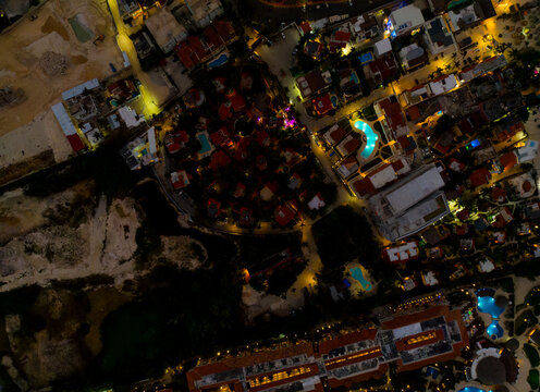 A nighttime aerial view of a city with a large pool and many buildings