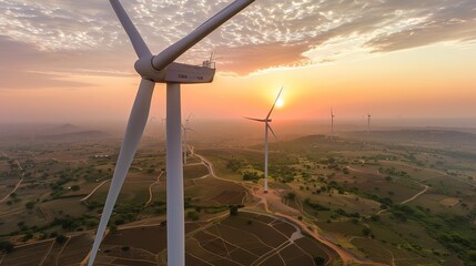 A drone photo of wind turbines against the backdrop of an Indian landscape at sunset.