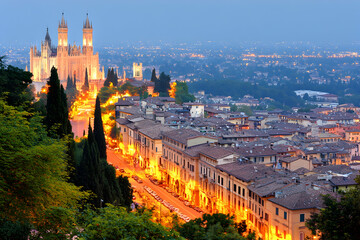 Naklejka premium Breathtaking twilight view of Verona, Italy, showcasing the illuminated city streets, Duomo, and surrounding hills.