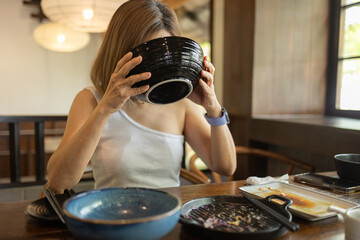 Woman is happily eating ramen at a Japanese restaurant