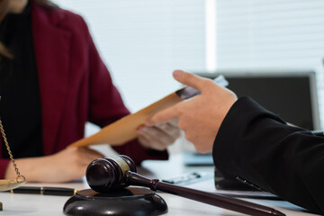 Male and female legal consultants work intently together over documents and laptops in a law office.