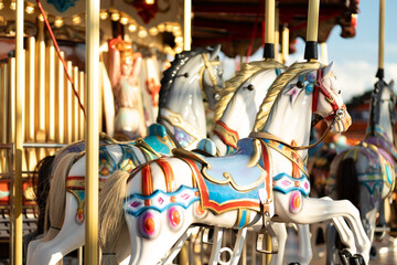 Closeup of horses on carnival Merry Go Round carousel at amusement park, with vibrant colors and...