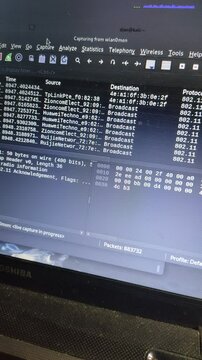 A close-up of a laptop screen running network packet analysis software on a Linux operating system. The interface displays data packets, sources, and protocols, commonly used for cybersecurity