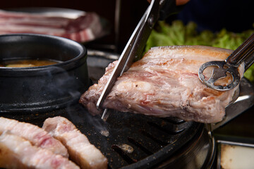 Cutting grilled pork belly with scissors