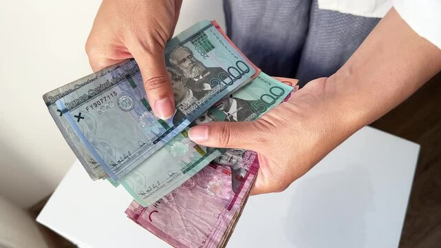 Close-up of hands holding Dominican pesos, 4K real-time video.