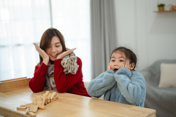 Joyful Moment of Asian Mother and Daughter Playing Together at Home with Wooden Toys and Smiles in...