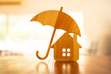 Model of umbrella with house on wooden table concept of the system of insurance savings and Housing...