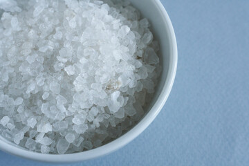 Close-up of sea salt in a bowl on a blue background