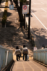 Two Schoolchildren Walking Down a Pedestrian Bridge