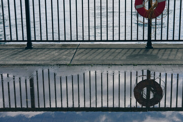 Lifebuoy Reflection in a Puddle Near Water