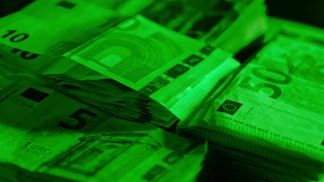 Euro bills stacked under green lighting, symbolizing money, power illicit wealth