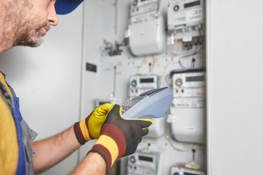 Technician reading consumption and charging on a wireless electricity power meter station in a building.