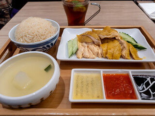 Hainanese Chicken Rice beautifully presented in a tray, serviced with three kinds of dipping sauce and a bowl of soup.