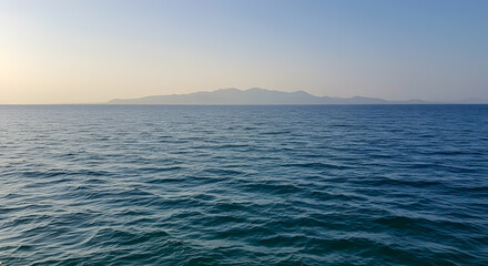 Obraz premium Serene Seascape: Distant Mountain Silhouette at Dawn