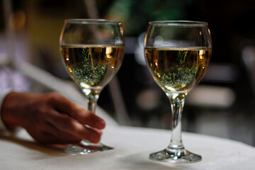 Holding 2 glasses of white wine with reflection in the glass