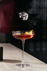 Manhattan cocktail with orange zest and ice cubes