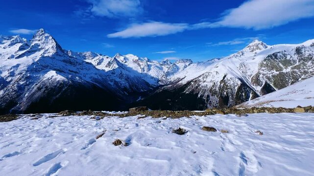 View of Dombay glaciers and mountain peaks in the winter sun. Panorama of the snow-capped Caucasus Mountains in sunny weather. Dombay-Ulgen and Moussa-Achitara mountains. Ski resort in Russia.