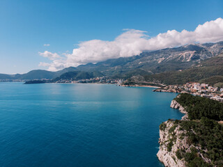 Green rocky shore of the Bay of Kotor overlooking the resort town at the foot of the mountains. Montenegro. Drone