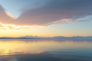 Obraz premium a tranquil lakeside scene at dawn or dusk, with a vast expanse of water reflecting the soft hues of the sky