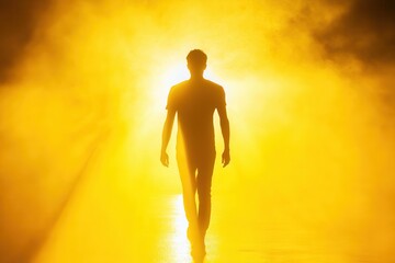 Obraz premium Silhouette of a man walking into a bright yellow light.