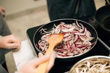 Onions are fried in a frying pan