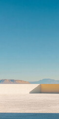 Naklejka premium Bright desert landscape under clear blue sky with distant mountains and modern architecture