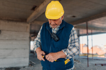 Senior construction worker pulling utility knife from pocket inside building shell