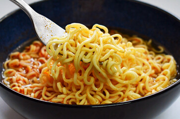 Instant noodles with fork in a bowl.