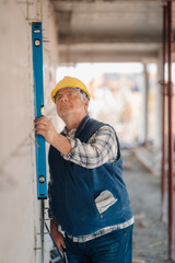 Senior construction worker using spirit level on building site