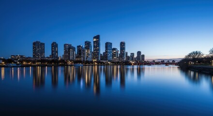 Naklejka premium City skyline at dusk reflecting on calm water with lights shimmering