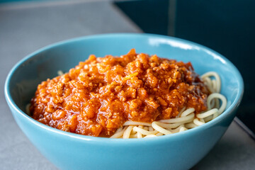 Spaghetti with rich tomato sauce in blue bowl