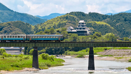 A limited express train on the Tokushima Line crossing the iron bridge over the Anabuki River in Ozu, Japan, Aug 2023