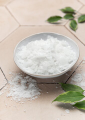 Magnesium chloride flakes in a bowl for spa treatment on tiled surface