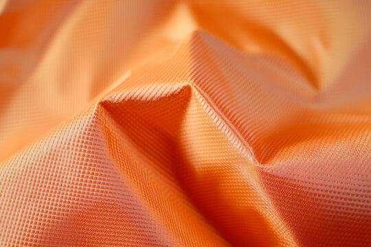 A rugged ripstop nylon fabric texture background in bright orange. The reinforced crosshatch pattern adds durability, making it ideal for outdoor gear, technical clothing, and performance textiles.