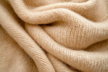 A soft, woven alpaca wool fabric texture background in warm camel beige. The fine, breathable fibers provide a plush, insulating effect, making it perfect for cozy winter scarves, high-end knitwear,