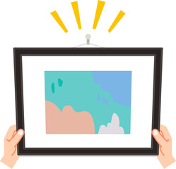 額縁を壁のフックにかける手