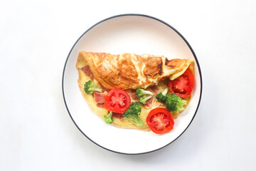 omelet with ham, tomato, broccoli in a plate isolated on white background
