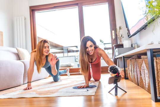 Two fitness influencers recording online yoga class at home