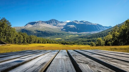 Fototapeta premium Landscape photograph of a majestic mountain range beneath a clear blue sky, with a wooden table in view. -