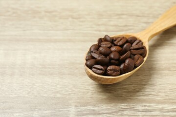 Coffee beans in a spoon on wooden background