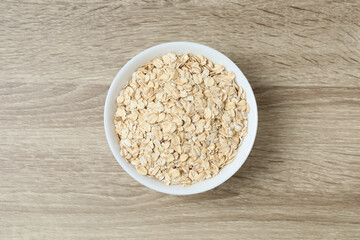Composition with oatmeal flakes on wooden background. Cooking breakfast