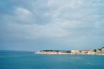 A scenic coastal view of a harbor with boats and buildings under a cloudy sky.