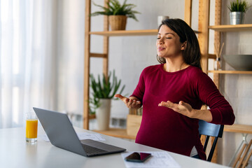 Pregnant woman using online app to practice breathing exercise while working from home.
