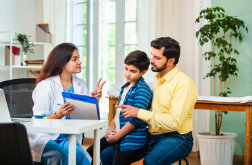 Caring Indian female doctor discussing prescription and medication with boy child patient, father